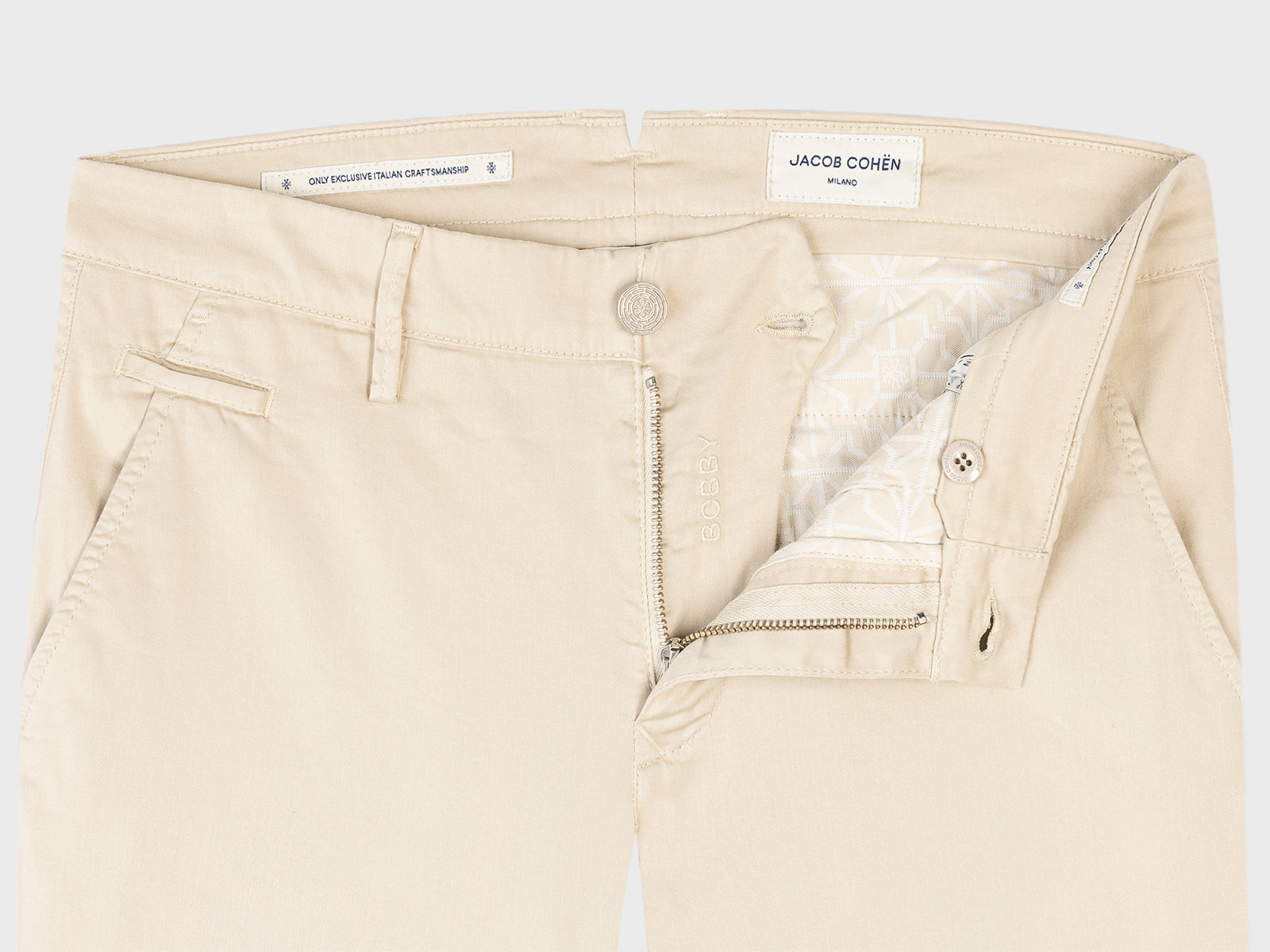 Beige pants with a brand label on a light gray background