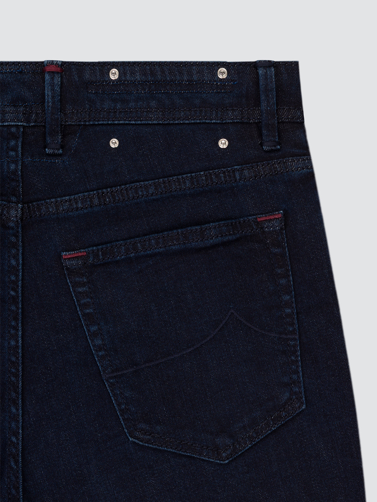 Close-up of the back pocket and waistband of dark blue Bard jeans, showing the contrast stitching and the belt loops.