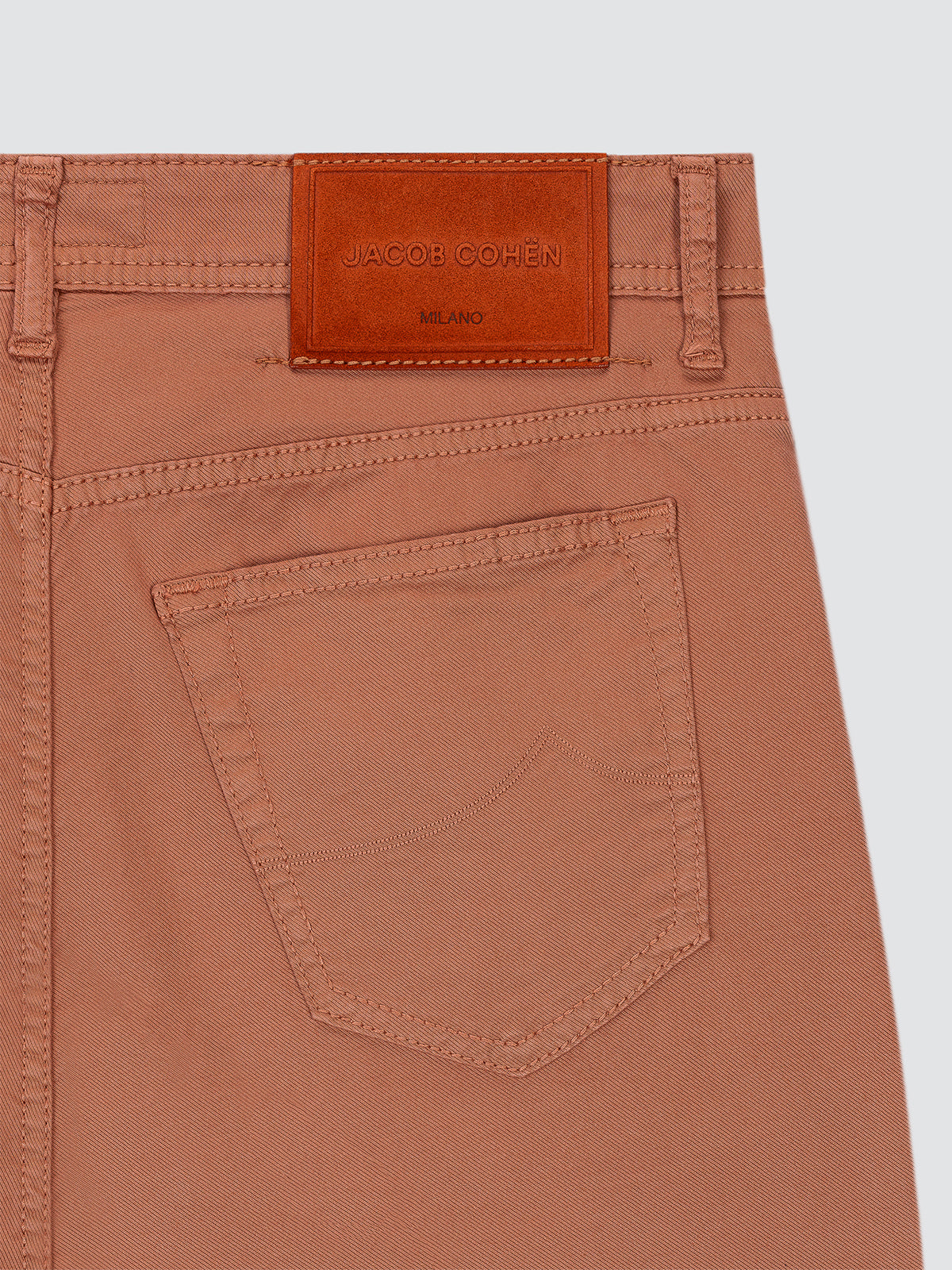 Terracotta 5 pockets pants with a leather patch and brand logo on a light gray background