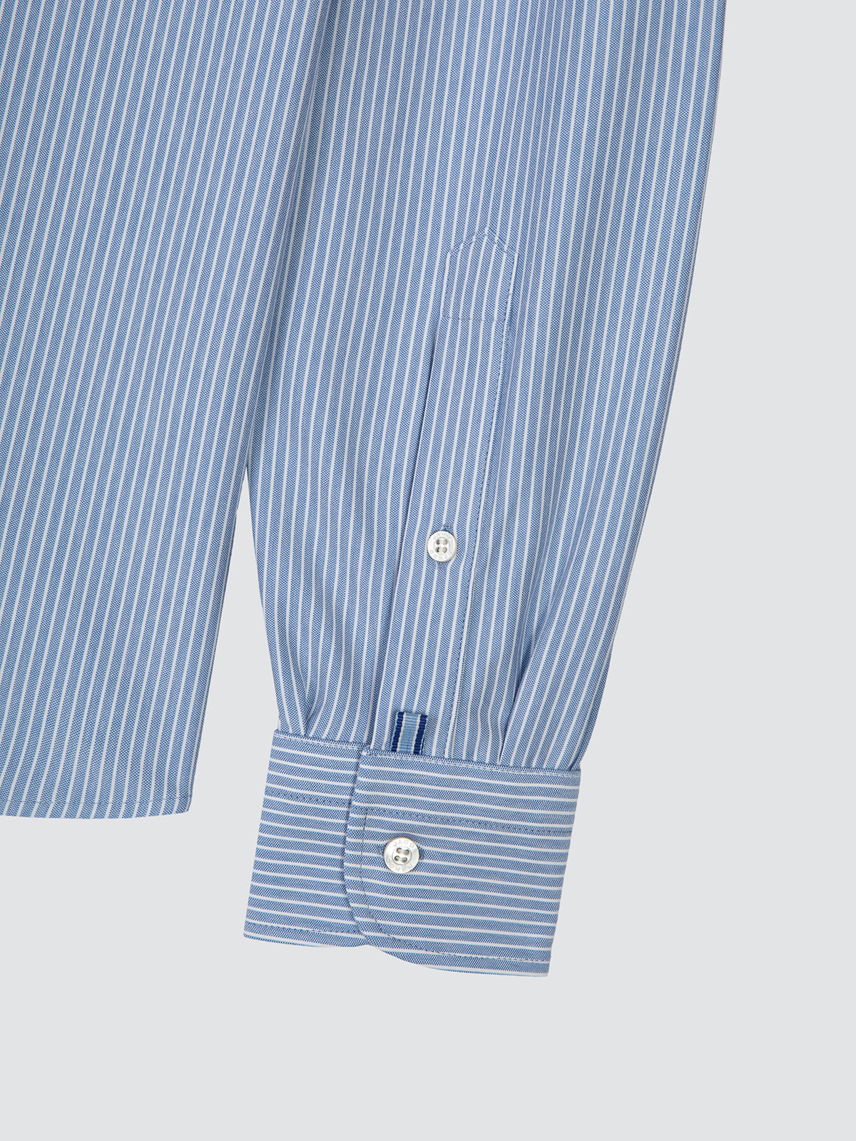 Close-up of the double cuff and mother-of-pearl button of the striped shirt