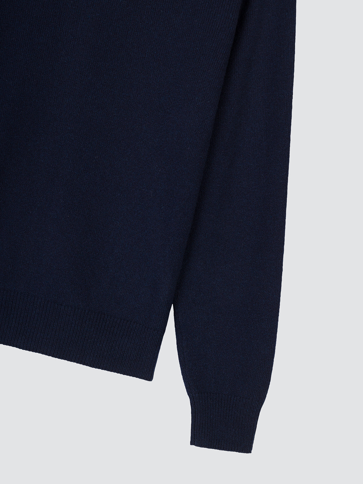 Close-up of the sleeve and ribbed cuff of the navy blue zip cardigan