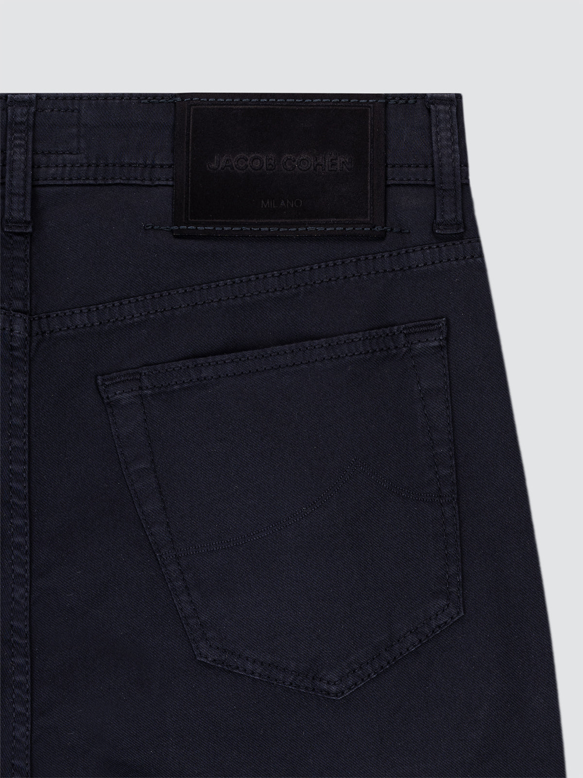 Close-up of black pants with a visible brand label on a light gray background