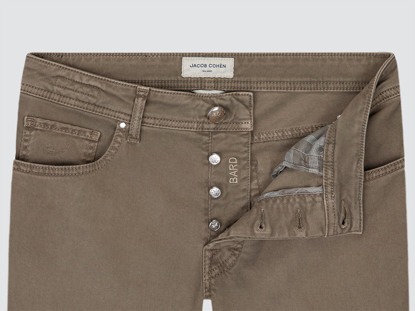 Close-up of a pair of brown denim jeans by Jacob Cohen, showing the front button closure, belt loops, and a partially opened front pocket revealing a patterned lining.