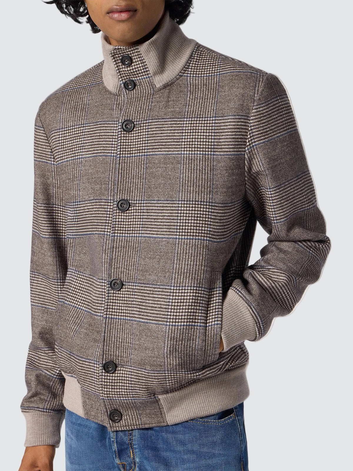 Model wearing the Prince of Wales check wool flannel bomber jacket, buttoned, over blue jeans, seen from the front.
