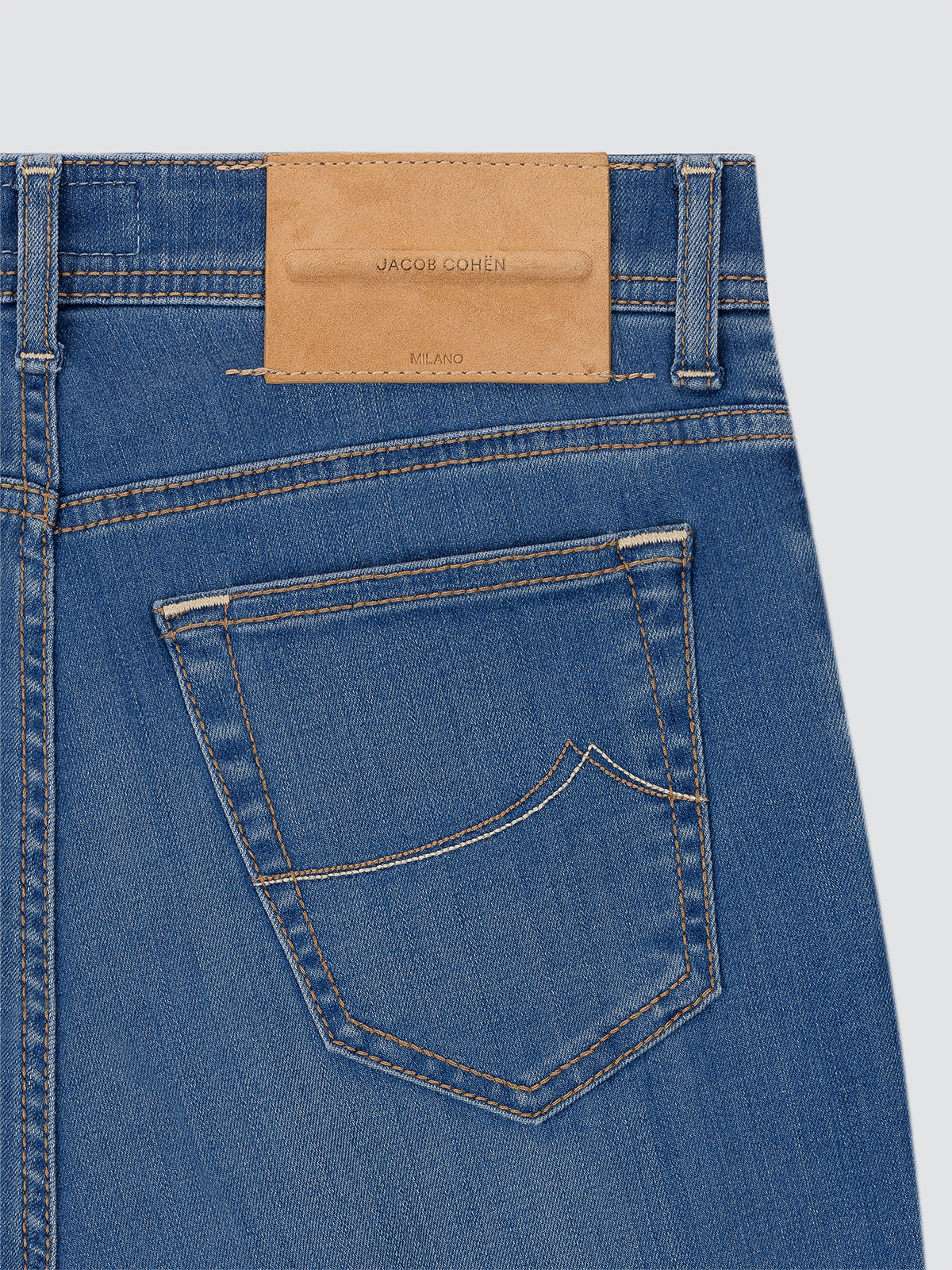 Close-up of blue jeans Jacob cohen with a brown leather patch on a light gray background