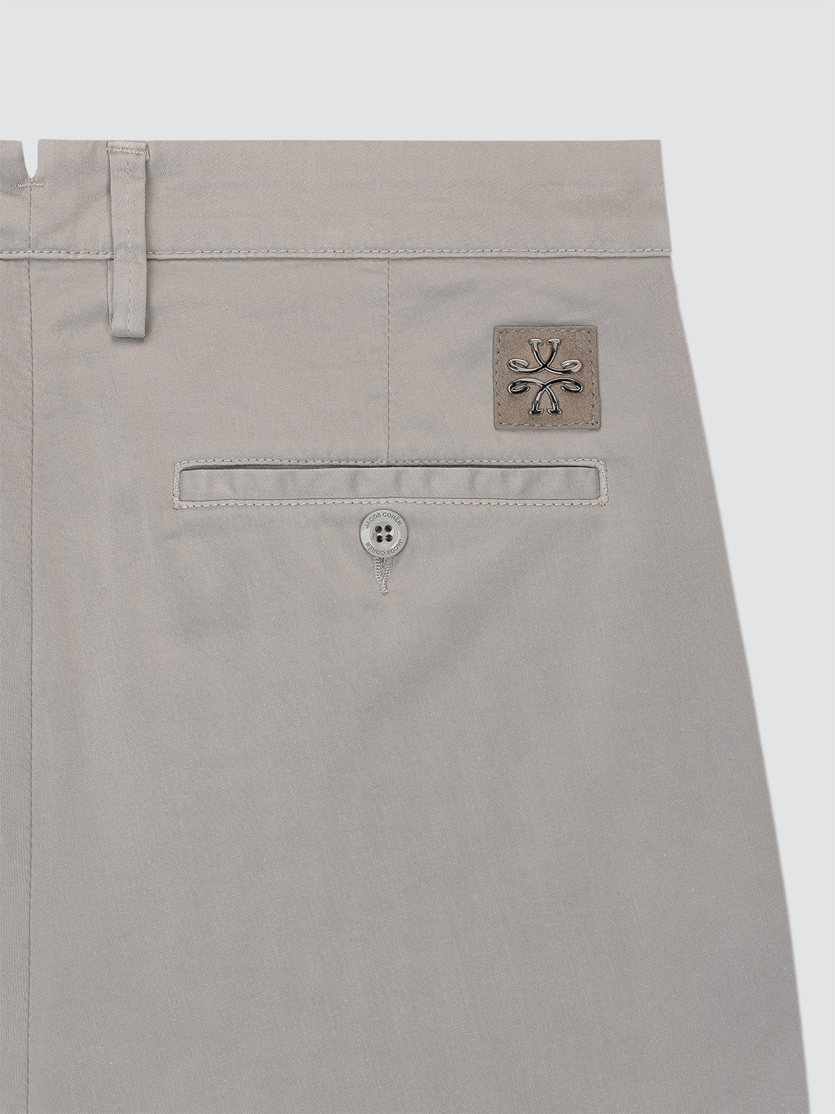 Close-up of a gray pants pocket with a brand logo Jacob Cohen on a light gray background