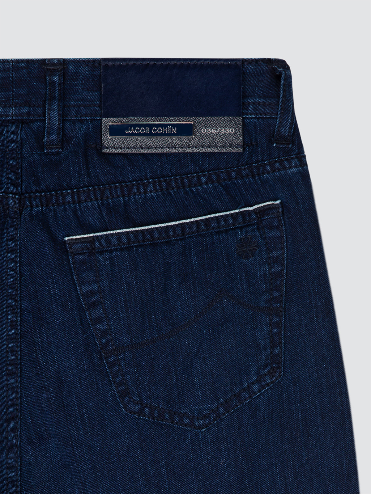 Close-up of blue denim jeans with a brand label on a light gray background