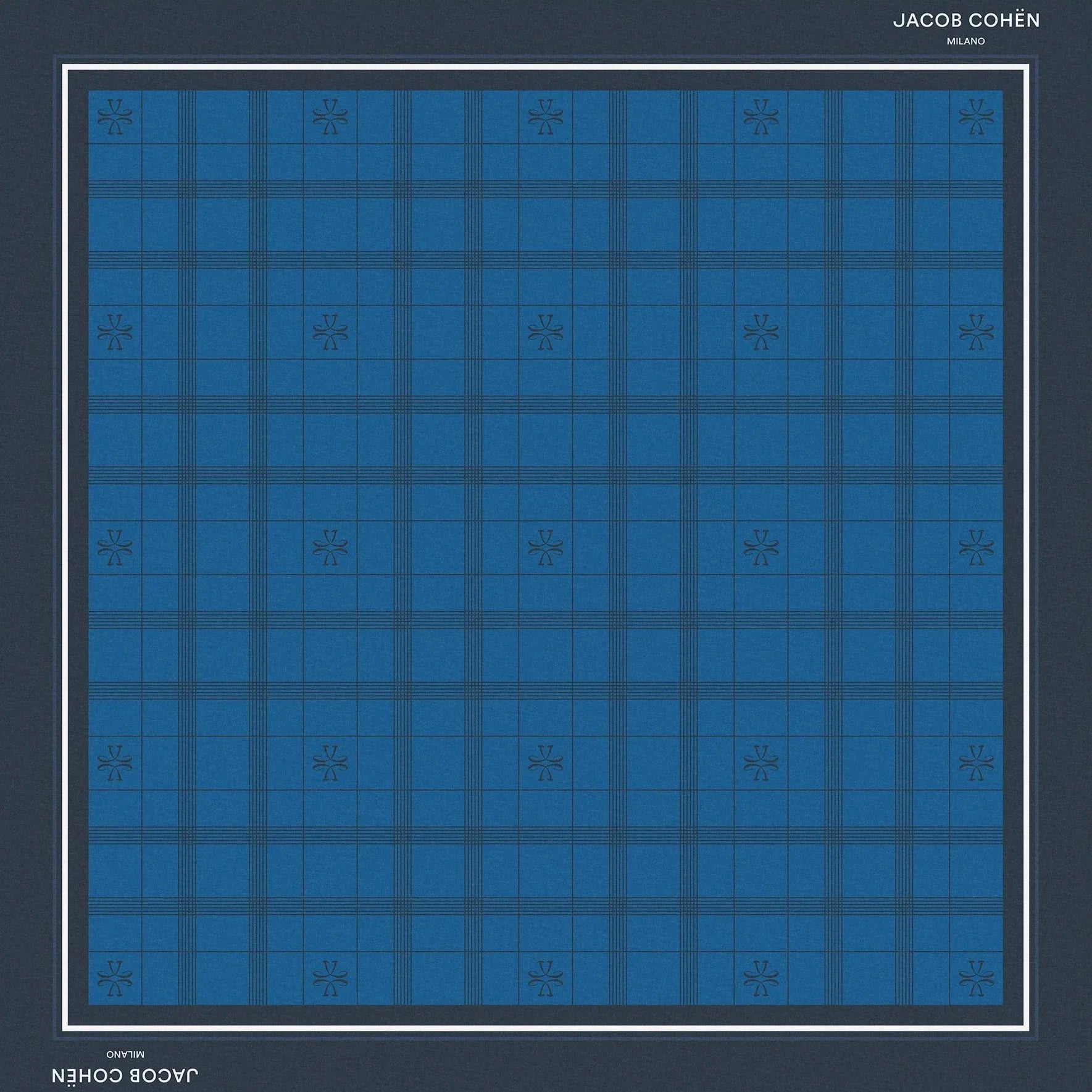 A square bandana featuring a blue and navy tartan plaid pattern, framed by a dark navy border with white text reading 'JACOB COHEN MILANO' at the top and bottom, set against a solid beige background.