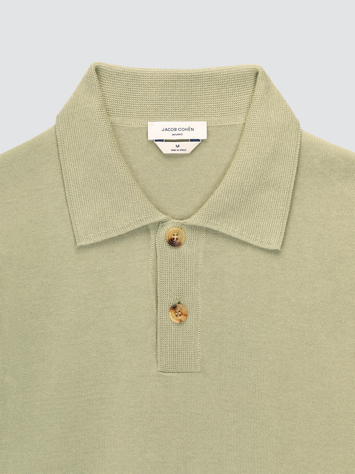 close up on Green polo shirt with a collar and buttons on a light gray background