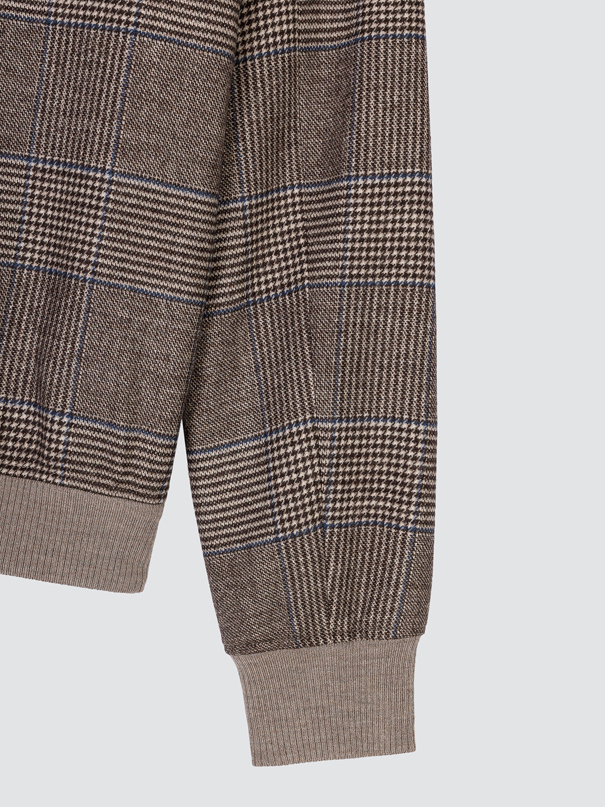 Close-up of the sleeve of the Prince of Wales check jacket, showing the beige ribbed cuff.
