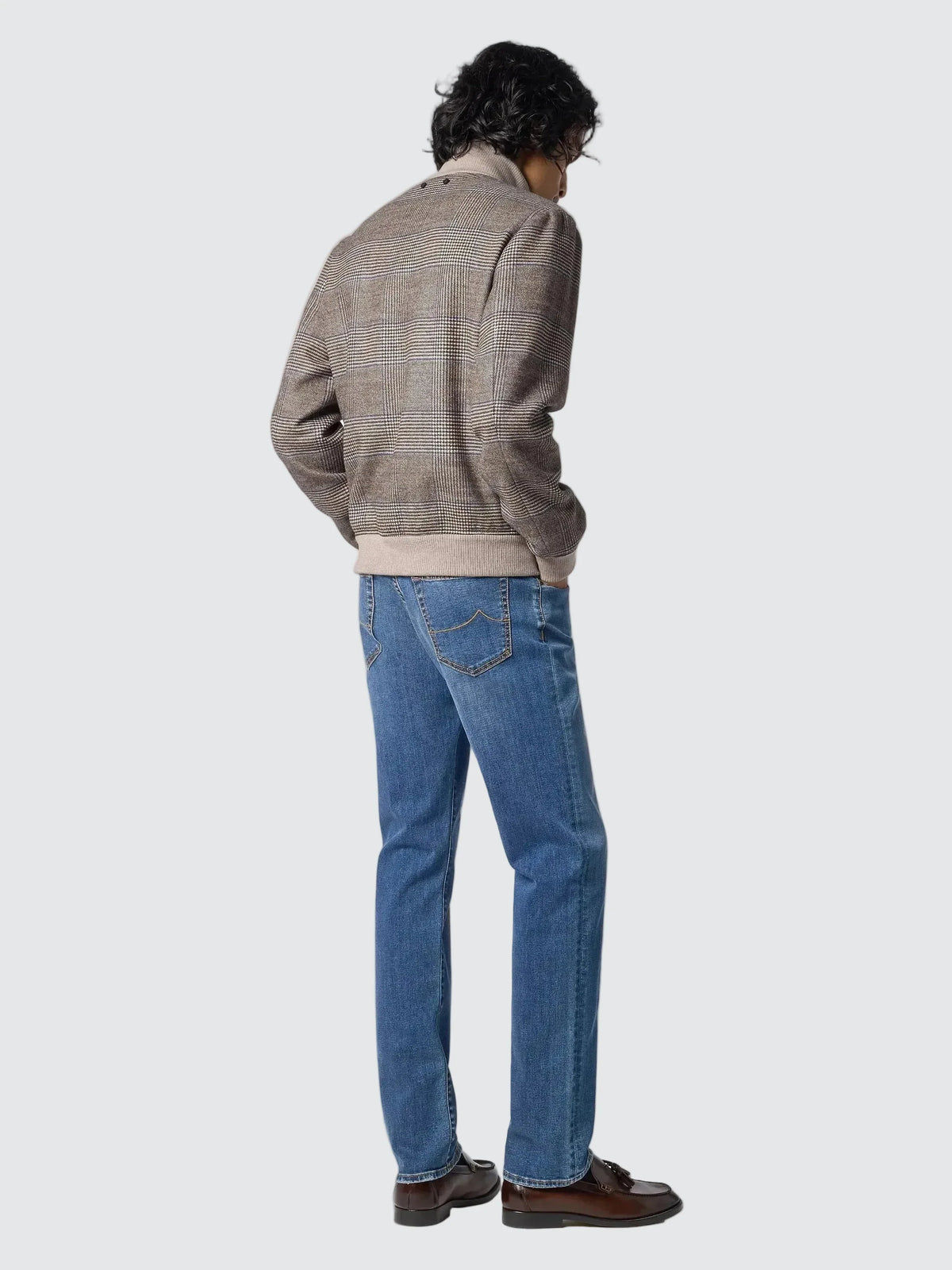 Model seen from behind wearing the Prince of Wales check bomber jacket with blue jeans and brown leather shoes.