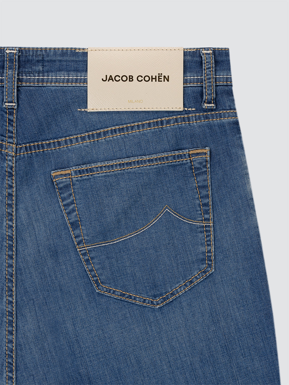 Close-up of blue jeans with a Jacob Cohen label on a white background