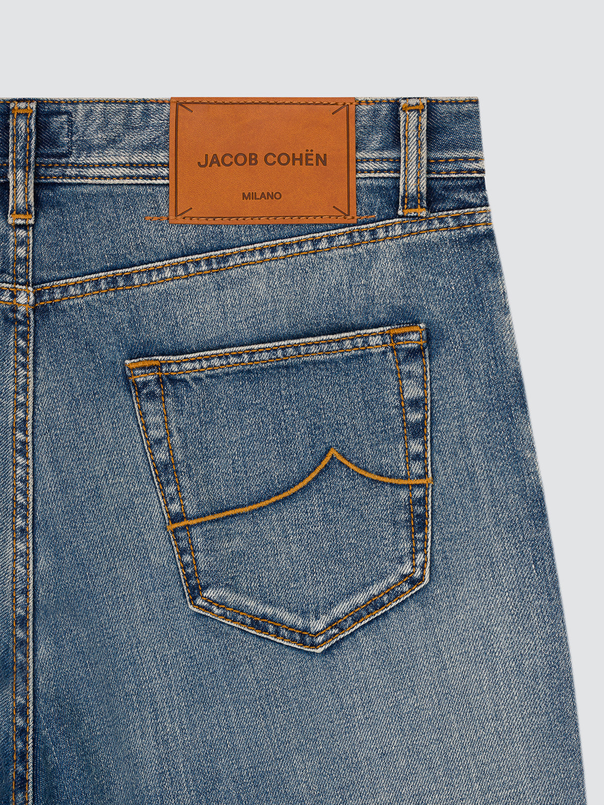Close-up of the back pocket of the Jude jeans, showing the tan leather patch with the Jacob Cohën Milano stamp and the contrast arcuate stitching.