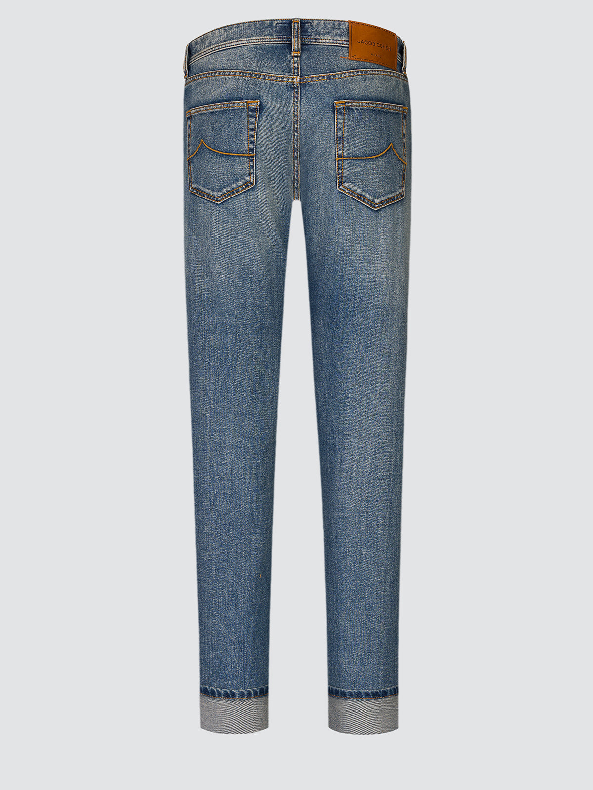 Full-length back view of the Jude jeans laid flat, showing both back pockets and the leather patch at the waistband.
