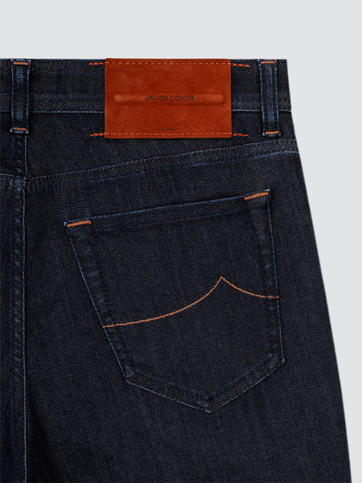 Dark blue jeans Jacob Cohen Nick-slim with a red leather patch on a light gray background