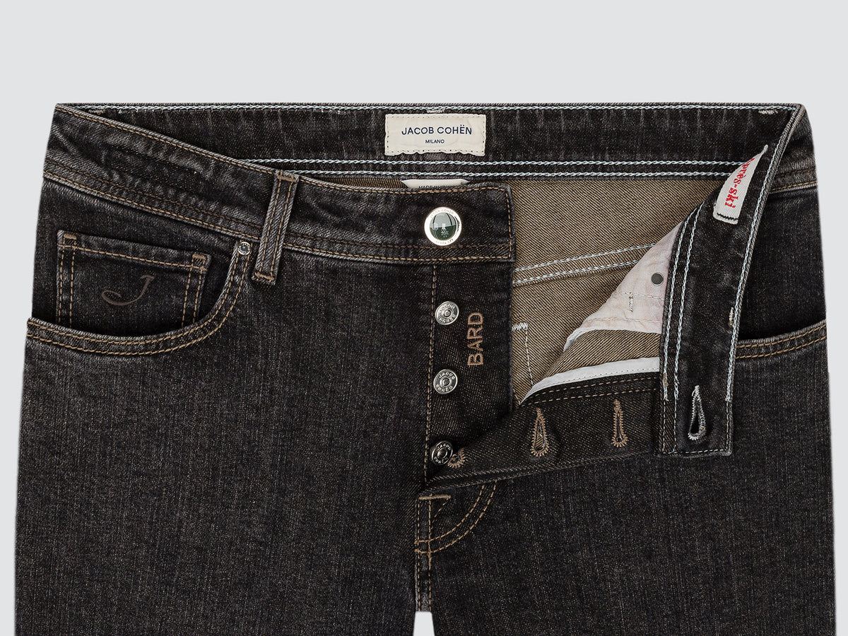 Close-up of the open button fly of the black Bard jeans, showing the Bard-engraved buttons