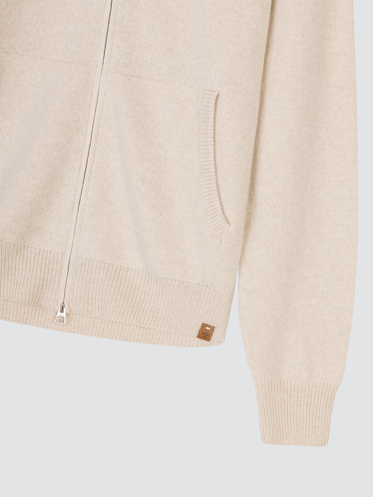 Close-up of the side pocket and ribbed cuff of the cream zip cardigan