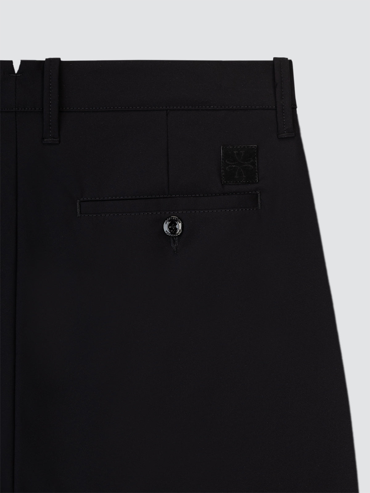 Close-up of black short in microfibre with a button on a light gray background
