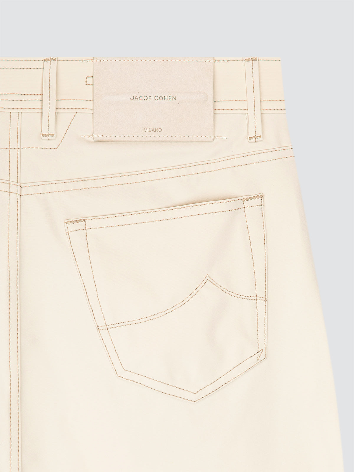 Close-up of beige pants traveller microfibre  with a brand label Jacob Cohen  on a grey background