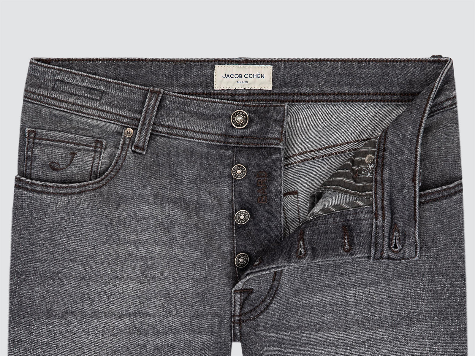 Close-up of a pair of dark gray denim jeans by Jacob Cohen, showing the button fly, front pockets, and a ripped detail on the right leg.