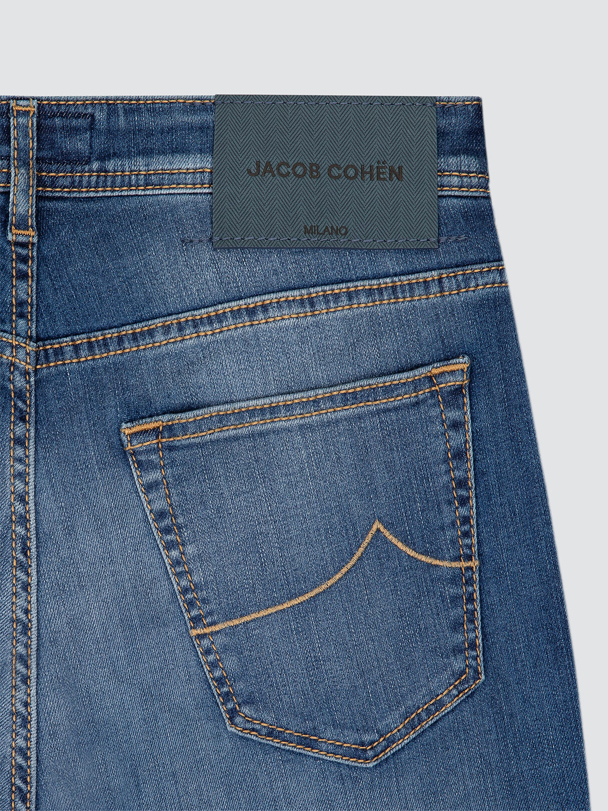 Close-up of a blue denim pocket on jeans with a white background